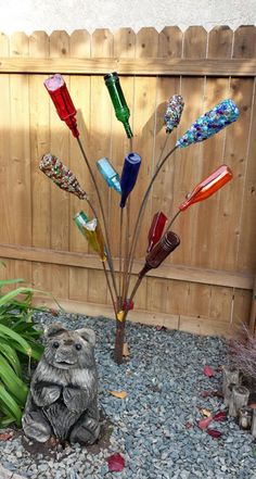 a statue of a bear sitting next to a tree made out of glass bottle caps