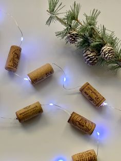 some wine corks are lit up with christmas lights and pine cones on the table