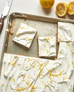 lemon bars with white frosting and yellow sprinkles on a baking sheet