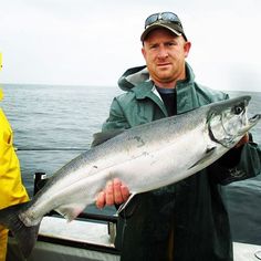 a man holding a fish while standing on a boat