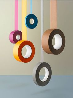 three rolls of colored tape hanging from strings