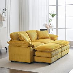 a living room with a yellow sectional couch and white curtains on the window sill