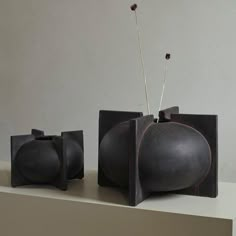 two black vases sitting on top of a shelf