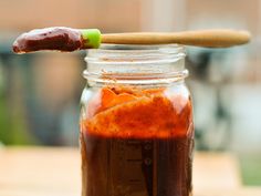 a jar filled with food sitting on top of a table next to a wooden spoon