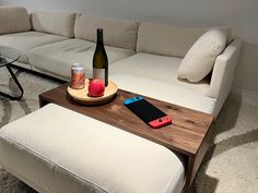 a table with a bottle of wine on it next to a couch and coffee table