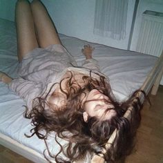 a woman laying on top of a bed with long hair