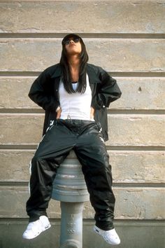 a woman sitting on top of a fire hydrant wearing black pants and white shirt