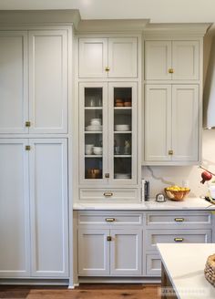 a kitchen with white cabinets and wooden floors