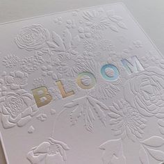 a close up of a paper with flowers on it and the word bloom written in gold foil