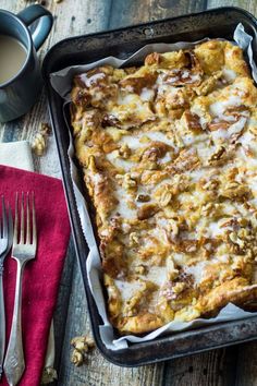 a casserole dish with cheese and nuts in it on a red napkin next to silverware