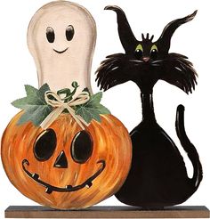 two halloween pumpkins with black cats on them and one has a ghost in the background