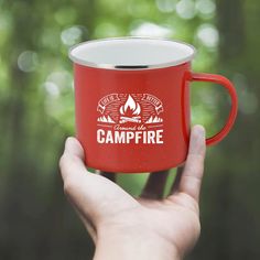 a person holding a red campfire mug in their hand