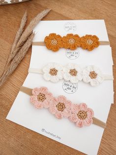 three crocheted flower headbands on top of a piece of paper