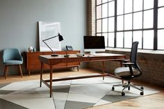 an office area with a desk, chair and computer on the floor in front of large windows