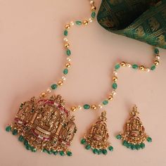 Description : This Kempu Nakshi long bead Pendant Set is a splendid representation of our artisanship, inspired by Indian culture and crafted with excellence. The Pendant has carved beads studded with stones in a cozy kempu setting, supporting the Lord Shiva and Goddess Parvati motif at the apex. Lord Ganesha and Kartikaya are sitting on the left and right side to bless your special occasion. Product Information : Materials used : 925 Silver with Antique Gold Plating Length: Pendant-30cm, Earrin Goddess Parvati, Ganesha Pendant, Indian Culture, Bead Pendant, Lord Ganesha, Lord Shiva, Pendant Set, Beaded Pendant, Ganesha