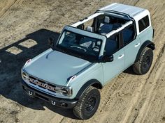 a light blue pick up truck driving down a dirt road