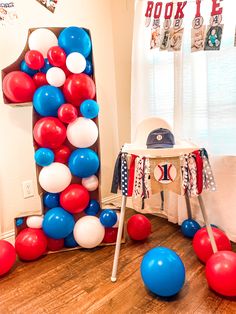 balloons and streamers are on the floor in front of a letter shaped balloon arch