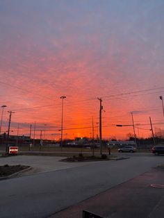 the sun is setting over a parking lot with cars parked on it and power lines in the background