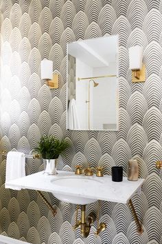 a white sink sitting under a bathroom mirror next to a wall mounted faucet