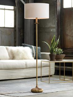 a living room with a white couch and a gold floor lamp in the middle of it