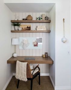 a wooden desk sitting in the corner of a room next to a wall mounted shelf