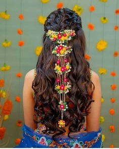 the back of a woman's head with flowers and beads in her long hair