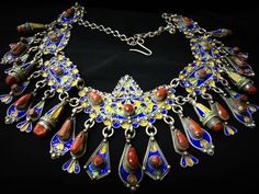 A magnificent ancient necklace from Algeria, from the greater Kabyle region, as it appears in the photos, the necklace is made of pure silver and decorated with blue, green and yellow enamel, and dotted with real cabochons of ancient coral. An incomparable necklace knotted with thick silver chains, you will find 25 silver pendants and inlaid with coral that add elegance and beauty. ** Length: 60 cm, adjustable. ** Height of pendant in the center of the necklace: 10 cm. ** width: 8 cm. ** Materia Ancient Necklace, Berber Jewelry, Ethnic Necklaces, Silver Chains, Antique Necklace, Upcycled Jewelry, Green And Yellow, Silver Pendants, Pure Silver