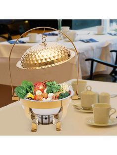 a large bowl filled with lots of food on top of a table next to cups and saucers