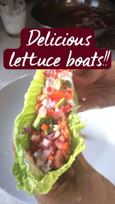 a person holding up a lettuce boat filled with veggies and sauce