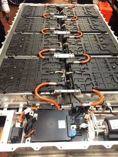 an assembly line with orange wires and black trays filled with electrical components on it