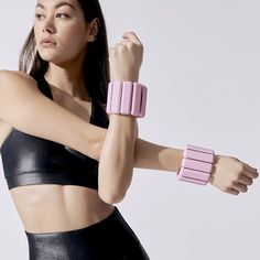 a woman in black sports bra top and pink wristbands posing for the camera