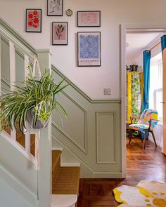 there is a potted plant on the stair case in this house with pictures above it