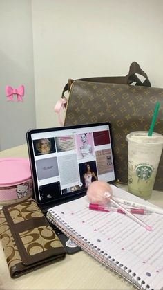 a laptop computer sitting on top of a desk next to a cup of coffee and notebook