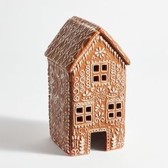 a small wooden house with intricate designs on the front and sides, sitting on a white surface