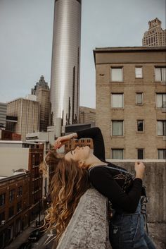 a woman leaning on the edge of a building with her hair blowing in the wind