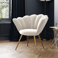 a white chair sitting on top of a hard wood floor next to a table and lamp