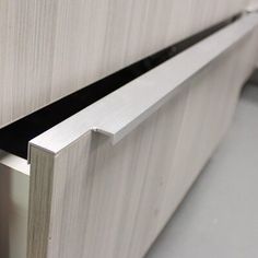 a close up view of the corner of a cabinet door with an aluminum strip on it