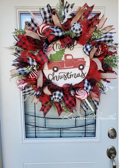 a christmas wreath on the front door of a house with red, white and black plaid ribbon