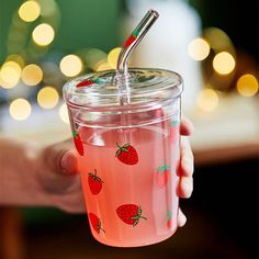 a person holding a glass with strawberries on it and a straw in the cup