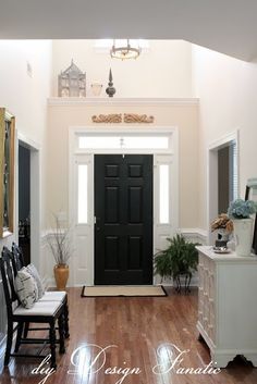 a black door is in the middle of a room with white walls and wood floors