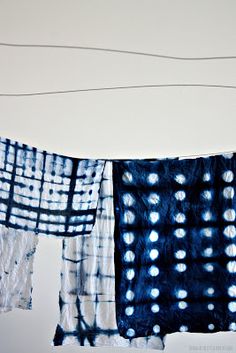 three pieces of cloth hanging on a line with wires in the background and one is blue and white