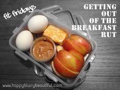 a plastic container filled with eggs, oranges and other food on top of a wooden table