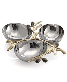 three metal bowls sitting on top of each other with olives in the middle and leaves