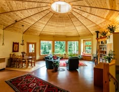 a living room filled with furniture and lots of windows next to a wooden ceiling covered in wood planks