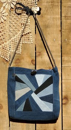 a blue bag hanging on a wooden fence with a doily in the back ground