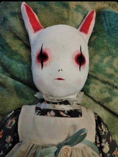 a white doll with red eyes laying on a green blanket