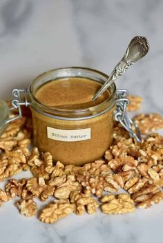 a jar filled with peanut butter surrounded by nuts