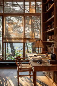 a desk with a lamp and bookshelf in front of large windows that look out onto the water