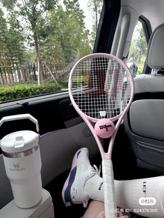 a pink tennis racket sitting in the back seat of a car