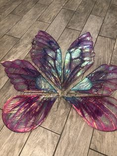 a purple and blue butterfly laying on top of a wooden floor